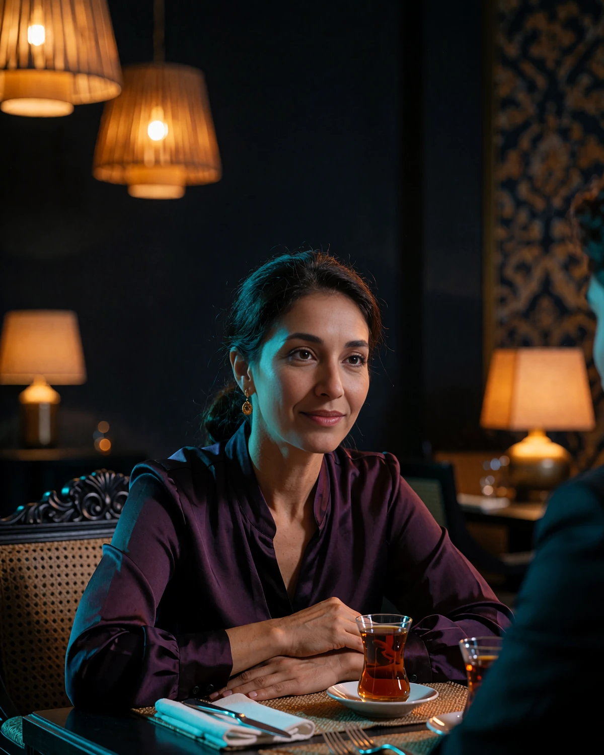 Poised Uzbek woman in a plum silk blouse seated at an upscale restaurant table during an evening conversation